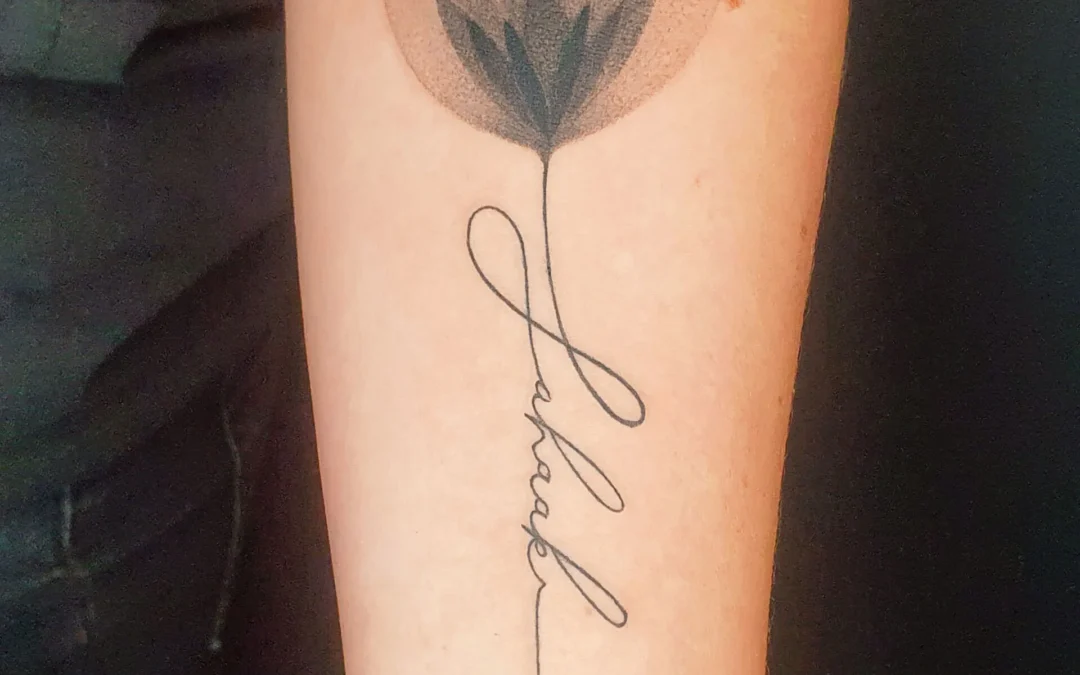 Fineline Tattoo Blume mit feiner Schrift Tattoo auf dem Arm