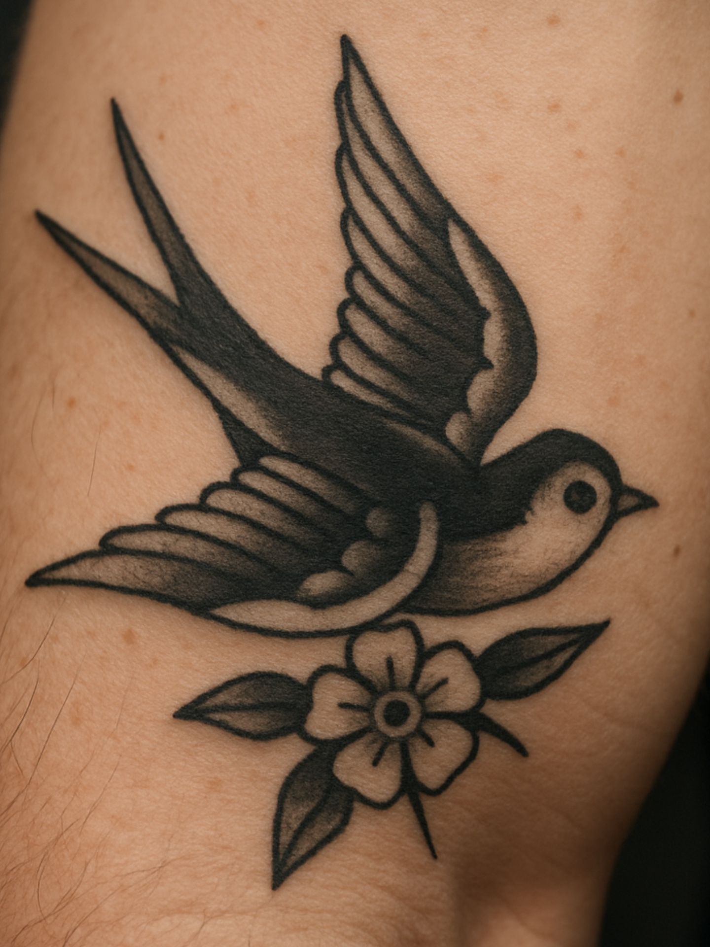 Old School Tattoo mit Schwalbe und Blume auf dem Arm