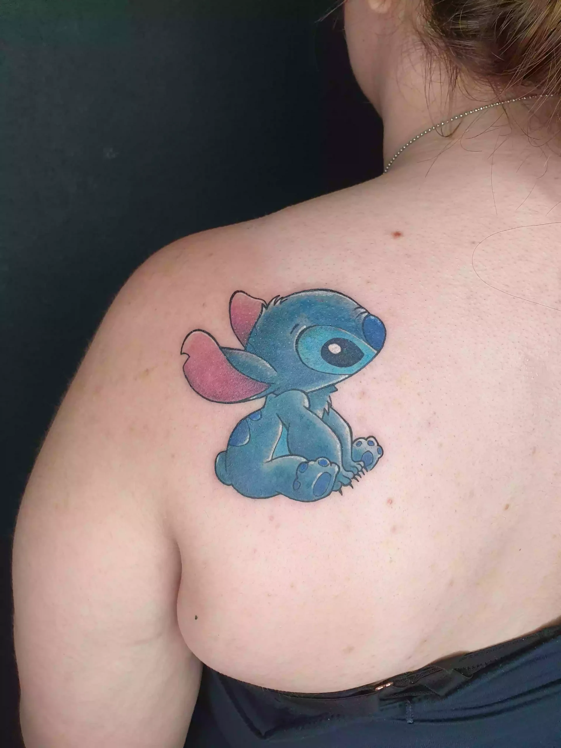 Farbiges Cartoon Tattoo von Stitch aus Lilo und Stitch auf dem Schulterblatt, gestochen bei EB Tattoo St. Gallen