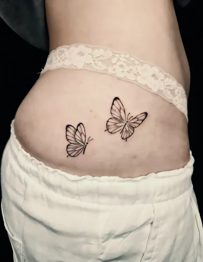 Zwei feine, realistische Schmetterlings-Tattoos im Fineline-Stil auf der Hüfte.