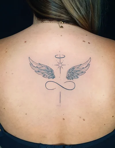 Fineline Tattoo mit Engelsflügeln, Unendlichkeitssymbol und Heiligenschein auf dem oberen Rücken.