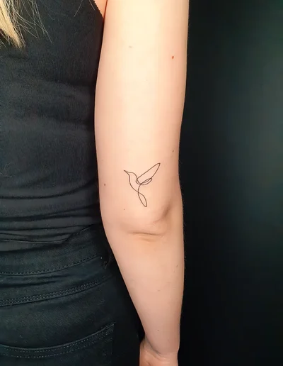Minimalistisches Fineline Kolibri-Tattoo am Arm.