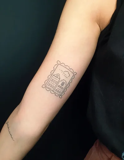 Fineline Tattoo eines Hauses im Briefmarken-Design auf dem Unterarm.