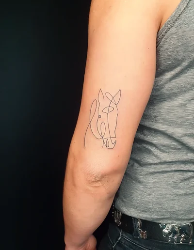 Minimalistisches Fineline-Tattoo eines Pferdekopfs als One-Line-Design auf dem Oberarm.