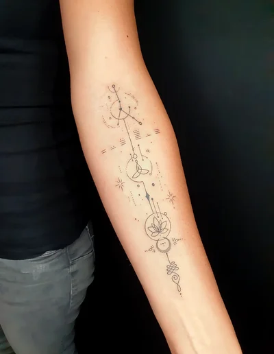 Geometric Fineline Tattoo mit Lotusblume und spirituellen Symbolen auf dem Unterarm.