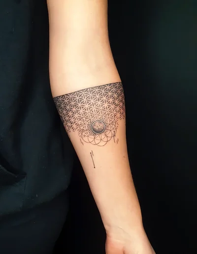 Geometrisches Mandala-Fineline-Tattoo mit Blume des Lebens und symmetrischem Muster auf dem Unterarm.