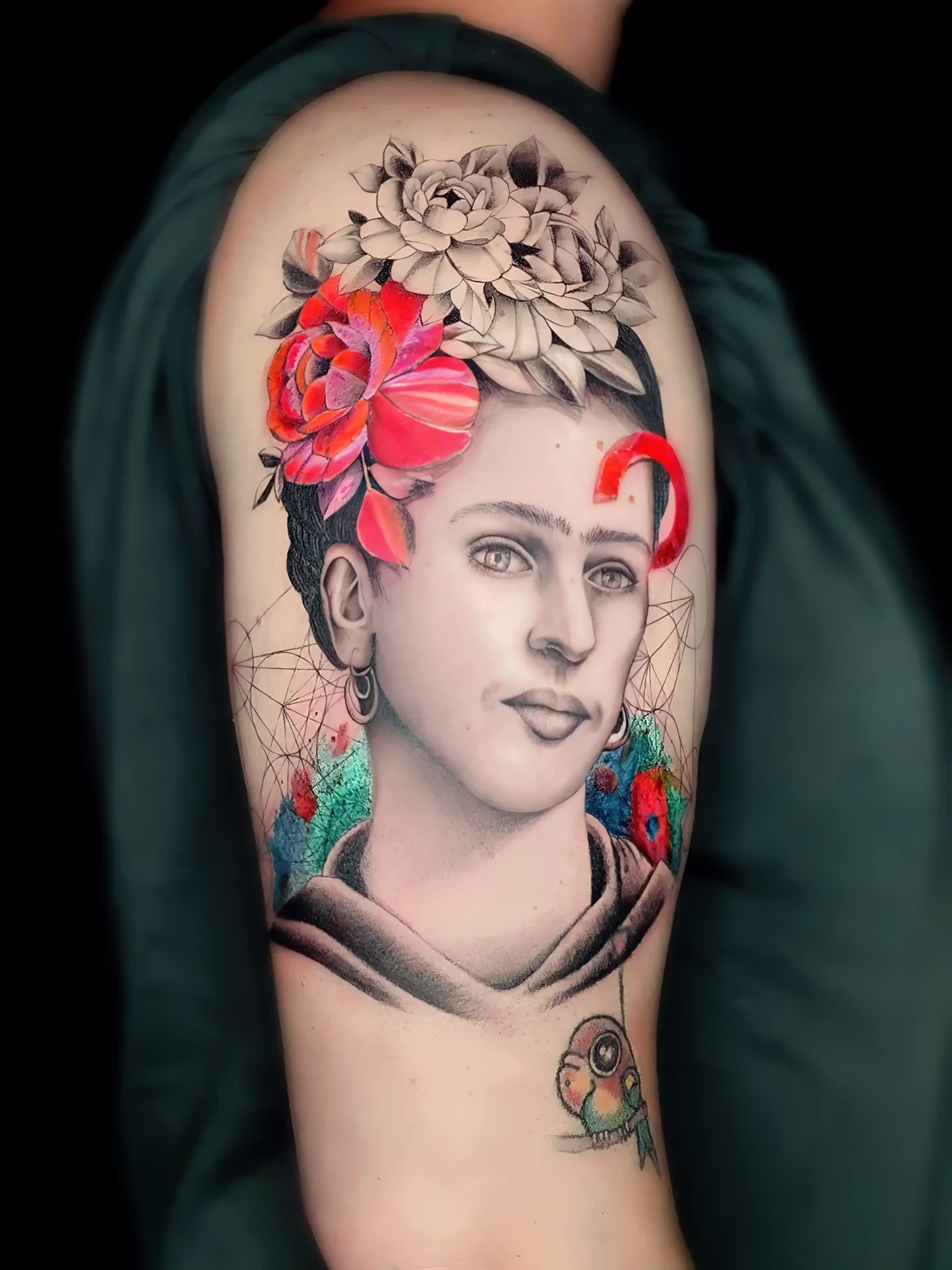 Realistic Tattoo eines Porträts mit Blumenkranz, geometrischen Elementen und Papagei auf dem Oberarm