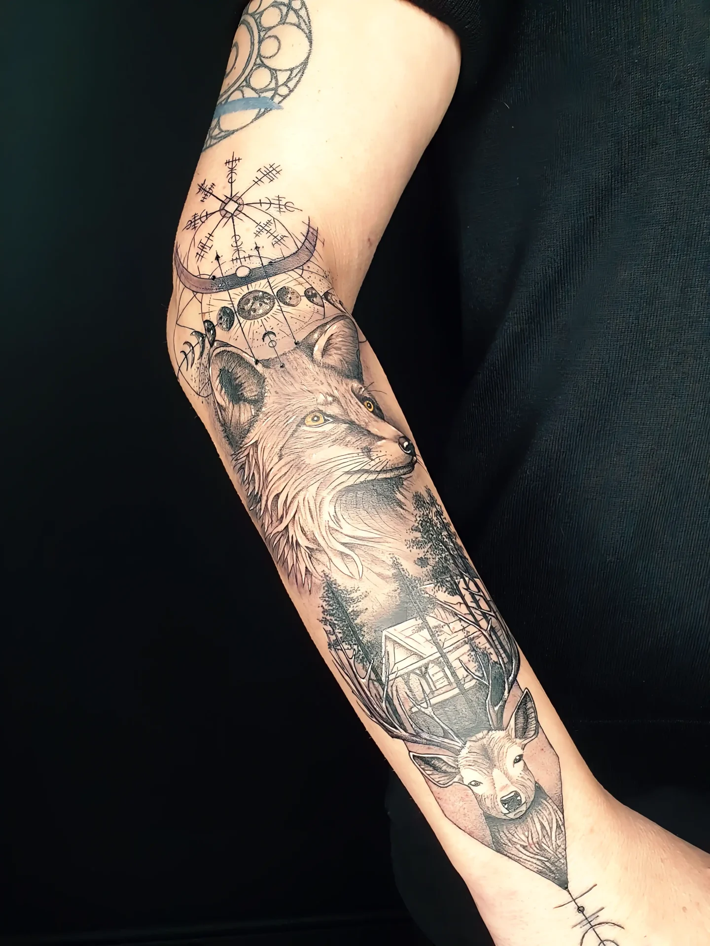 Realistic Tattoo eines Fuchses und Hirsches mit Wald, Hütte und mystischen Symbolen auf dem Unterarm.