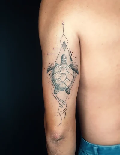 Realistic Tattoo einer Meeresschildkröte mit geometrischen Linien und abstrakten Elementen auf dem Oberarm.