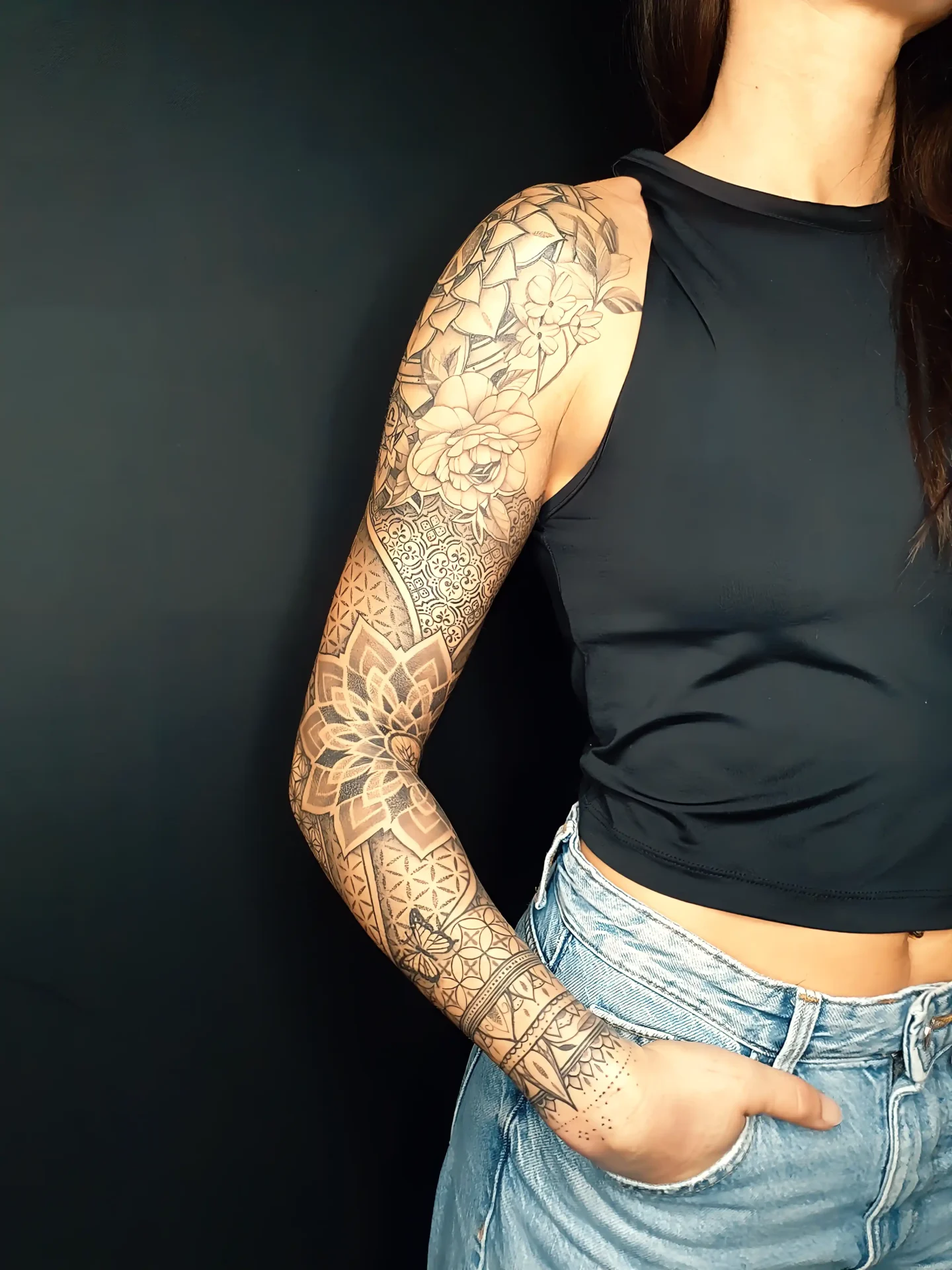 Full-Sleeve-Tattoo mit floralen Elementen, Mandalas und Dotwork-Mustern auf dem Arm einer Frau.