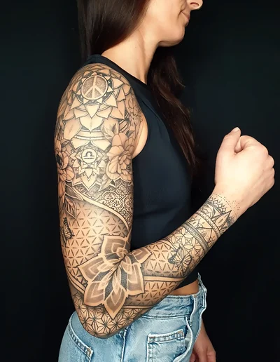 Komplexes Full-Sleeve-Tattoo im Mandala-, Geometrie- und Dotwork-Stil mit spirituellen Symbolen auf dem Arm einer Frau.