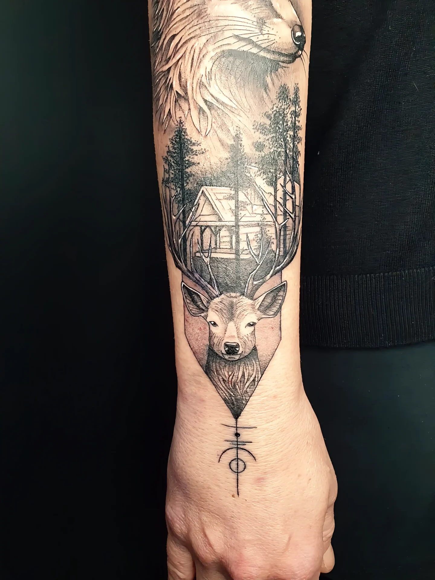 Storytelling Komposition mit Hirsch, Waldhütte und Wolf am Unterarm, gestochen bei EB Tattoo in St. Gallen
