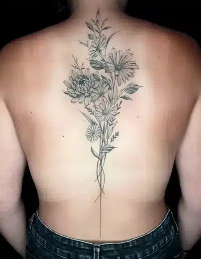 Großes Blumen Tattoo am Rücken mit Gänseblümchen und Blättern, gestochen bei EB Tattoo in St. Gallen – feine Linien und natürliche Schattierung