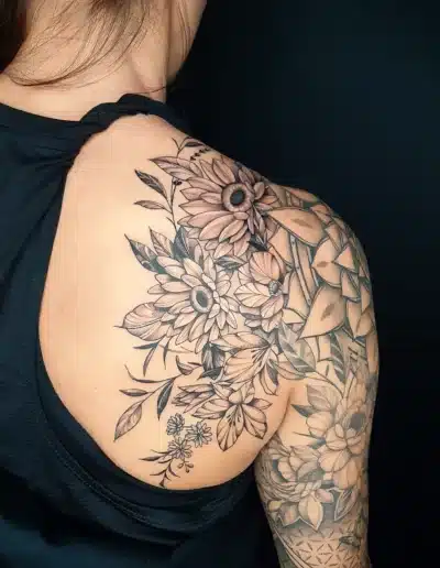 Großflächiges Blumen Tattoo über Schulter und Rücken bei EB Tattoo in St. Gallen – realistische Sonnenblumen und Blätter in Black &amp;amp; Grey