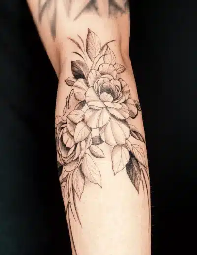 Feines Blumen Tattoo mit Rosen und Blättern am Arm, gestochen bei EB Tattoo in St. Gallen – Black &amp;amp; Grey mit realistischer Schattierung