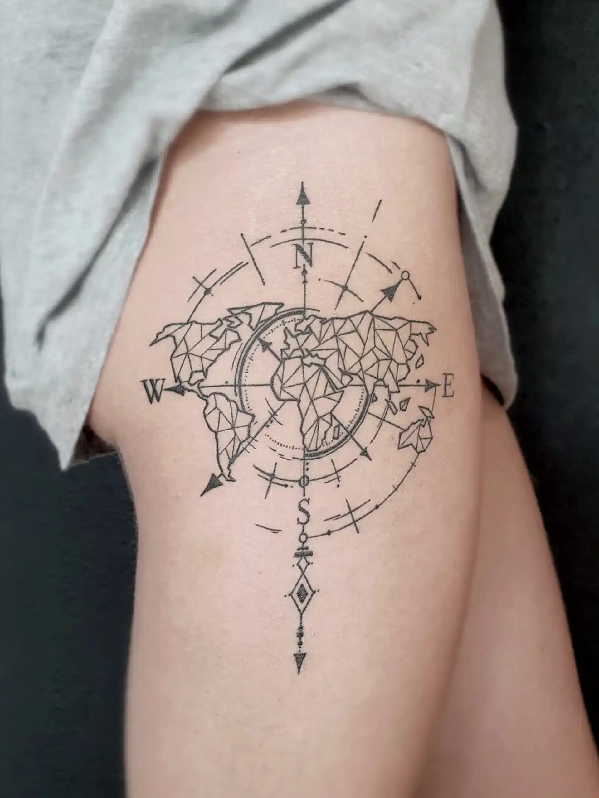 Kompass Tattoo mit geometrischer Weltkarte am Oberschenkel