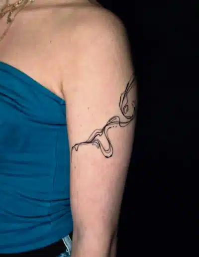 Abstraktes Linework Tattoo am Oberarm mit fließenden Linien, gestochen bei EB-Tattoo St. Gallen