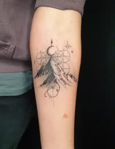 Geometrisches Berg Tattoo im Fineline-Stil mit Mond und Ornamenten am Unterarm bei EB-Tattoo St. Gallen