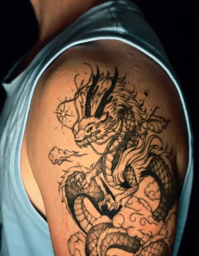 Japanisches Drachen Tattoo am Oberarm eines Mannes mit Schuppen, Wolken und feinem Linework, gestochen bei EB-Tattoo St. Gallen