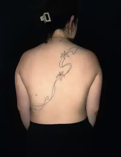 Fine Line Ruecken Tattoo mit Blumenlinien auf dem Ruecken einer Frau, gestochen bei EB-Tattoo St. Gallen