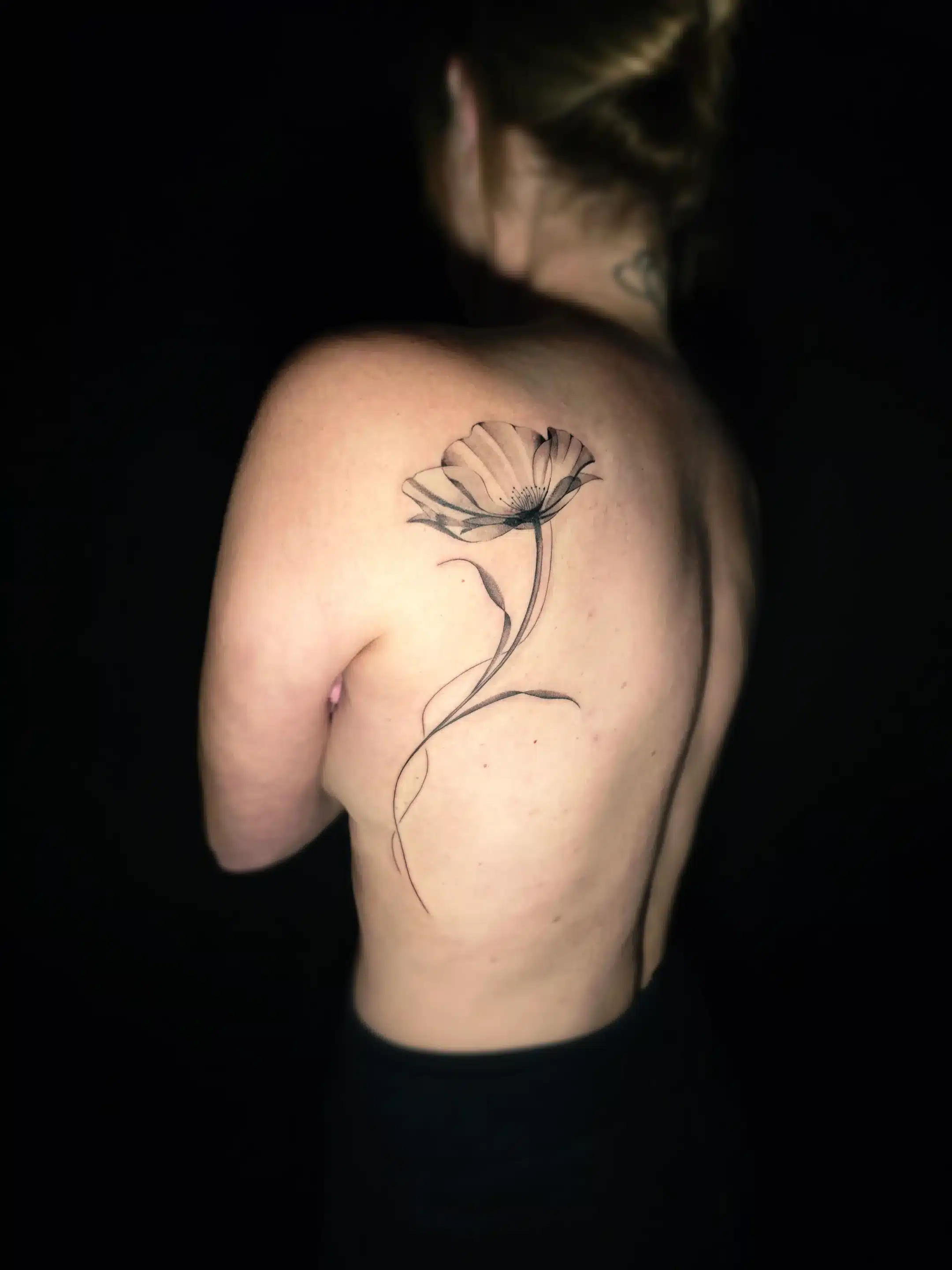 Zartes Fineline Blumen Tattoo am oberen Rücken in minimalistischer Linienführung bei EB-Tattoo St. Gallen