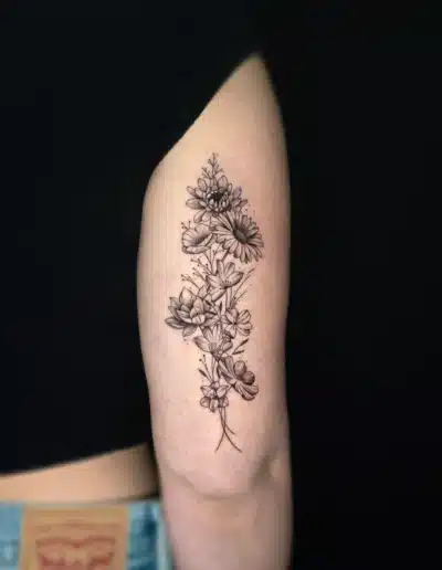 Fineline Blumenstrauss Tattoo mit filigranen Blüten am Oberarm bei EB-Tattoo St. Gallen