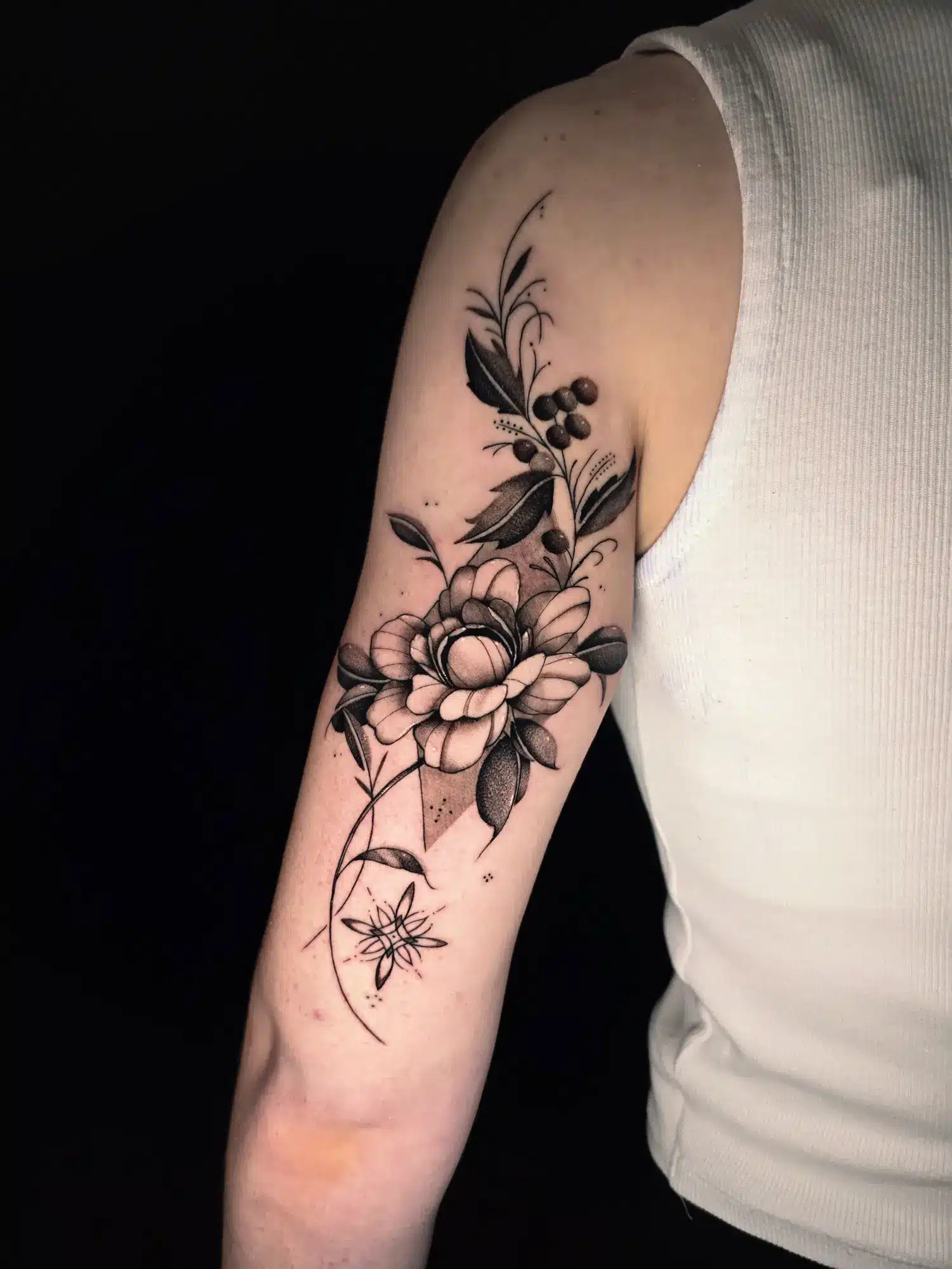 Realistisches Blumen-Tattoo mit Blättern und Beeren am Oberarm bei EB-Tattoo St. Gallen