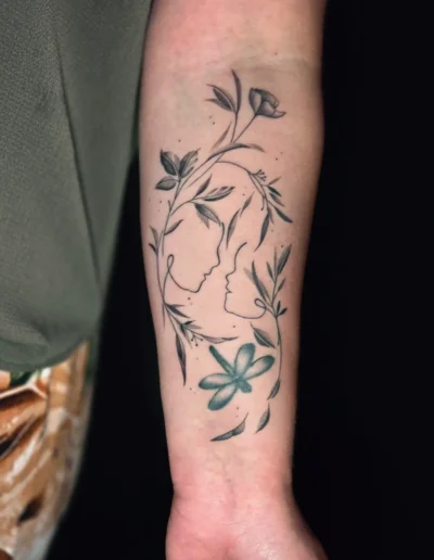 Feinliniges florales Tattoo mit zwei Gesichtssilhouetten und Blüten am Unterarm bei EB-Tattoo St. Gallen