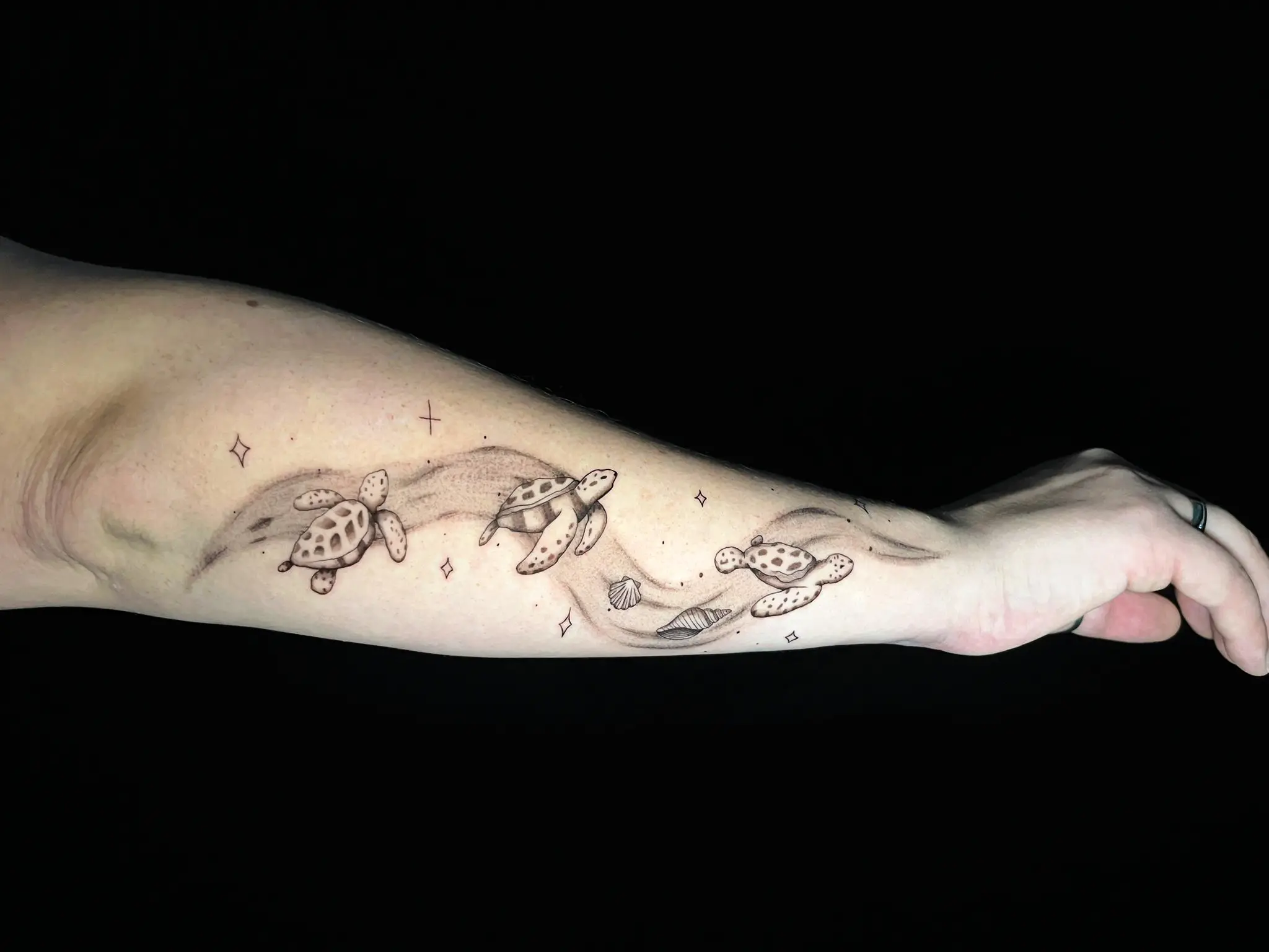 Fineline Unterarm-Tattoo mit mehreren Meeresschildkröten und Wellen bei EB-Tattoo St. Gallen