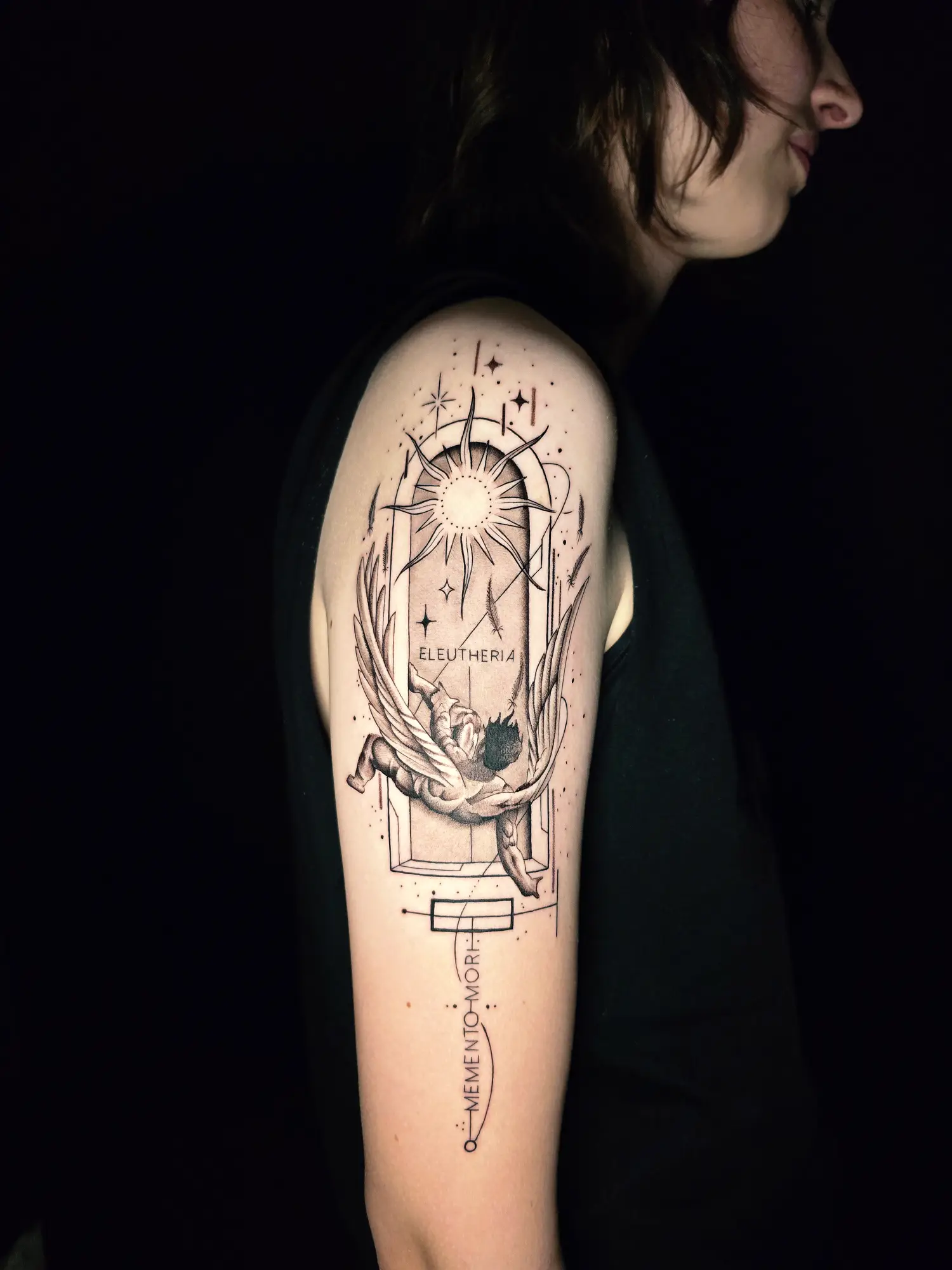 Geometrisches Engel Tattoo mit Memento Mori Schriftzug und Fineline Details am Oberarm bei EB-Tattoo St. Gallen