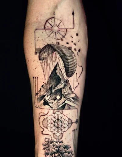 Geometric Natur Tattoo mit Berglandschaft, Gleitschirm, Kompass und Flower of Life am Unterarm, gestochen bei EB-Tattoo St. Gallen