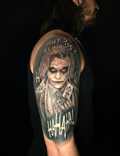 Realistisches Joker Portrait Tattoo mit Schriftzügen am Oberarm bei EB-Tattoo St. Gallen