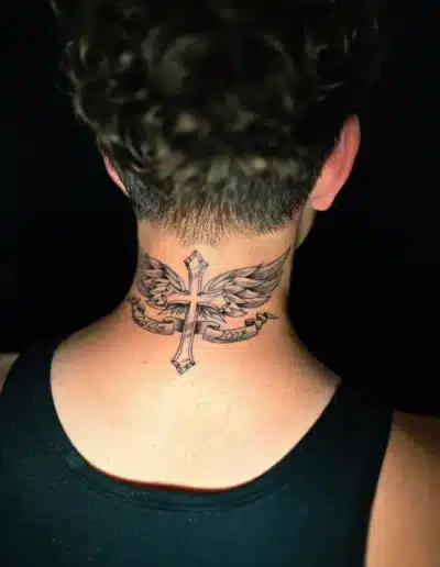 Traditionelles Kreuz-mit-Flügel Tattoo im Nacken mit Banner und Datum bei EB-Tattoo St. Gallen