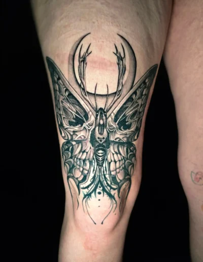 Blackwork Motten Tattoo mit Hörnern und detaillierten Flügelstrukturen am Knie, gestochen bei EB-Tattoo St. Gallen