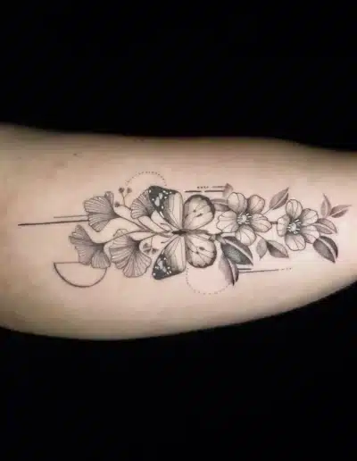 Fine-Line Schmetterling und Blumen Tattoo am Oberarm, zart schattiert, gestochen bei EB-Tattoo St. Gallen