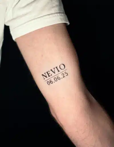 Schriftzug Tattoo mit dem Namen „Nevio“ und Datum am Oberarm, gestochen bei EB-Tattoo St. Gallen