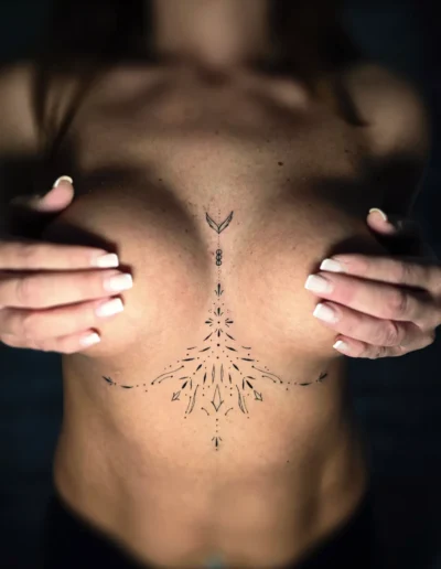 Feinliniges Underboob Tattoo mit ornamentalen Linien bei EB-Tattoo in St. Gallen