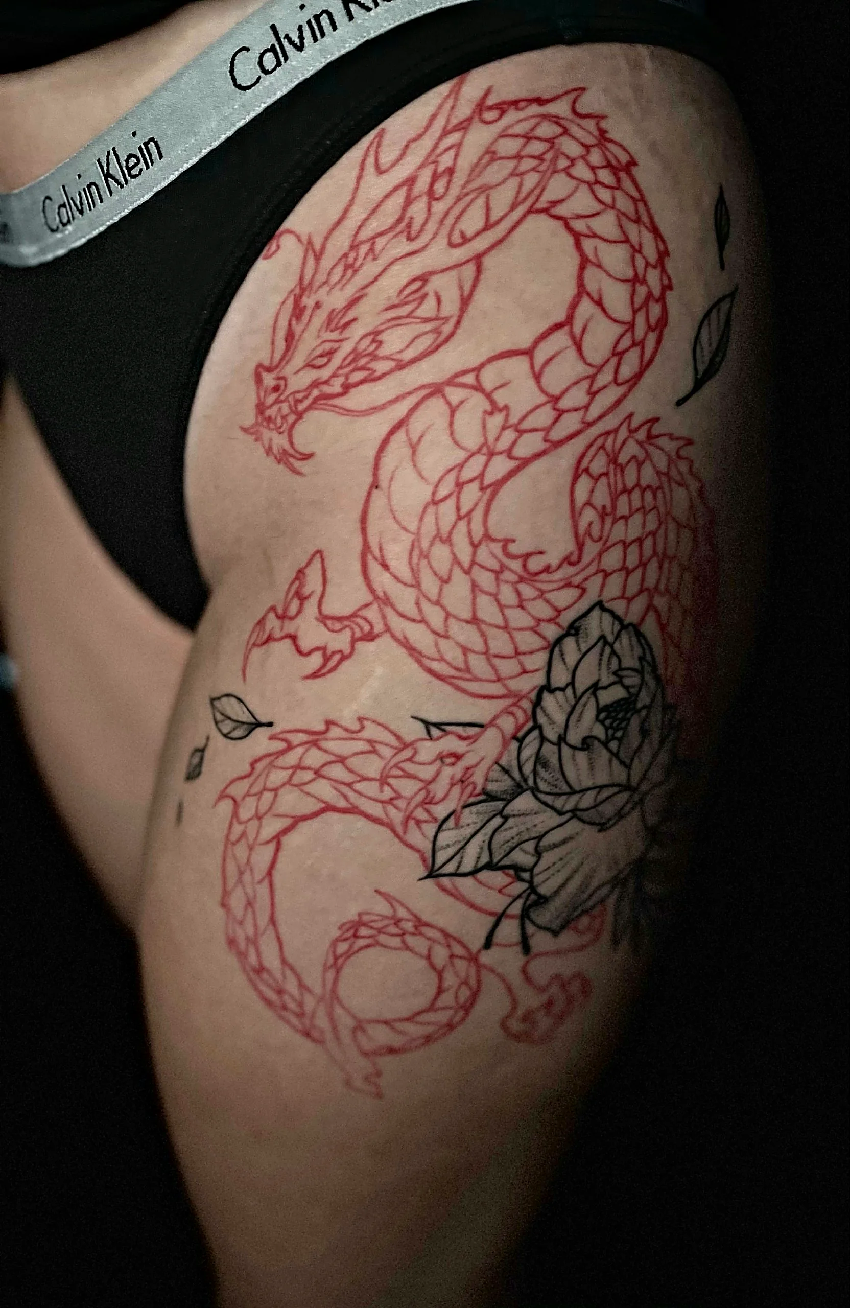 Drachen Tattoo in Red Ink am Oberschenkel, gestochen von Jens bei EB Tattoo St. Gallen