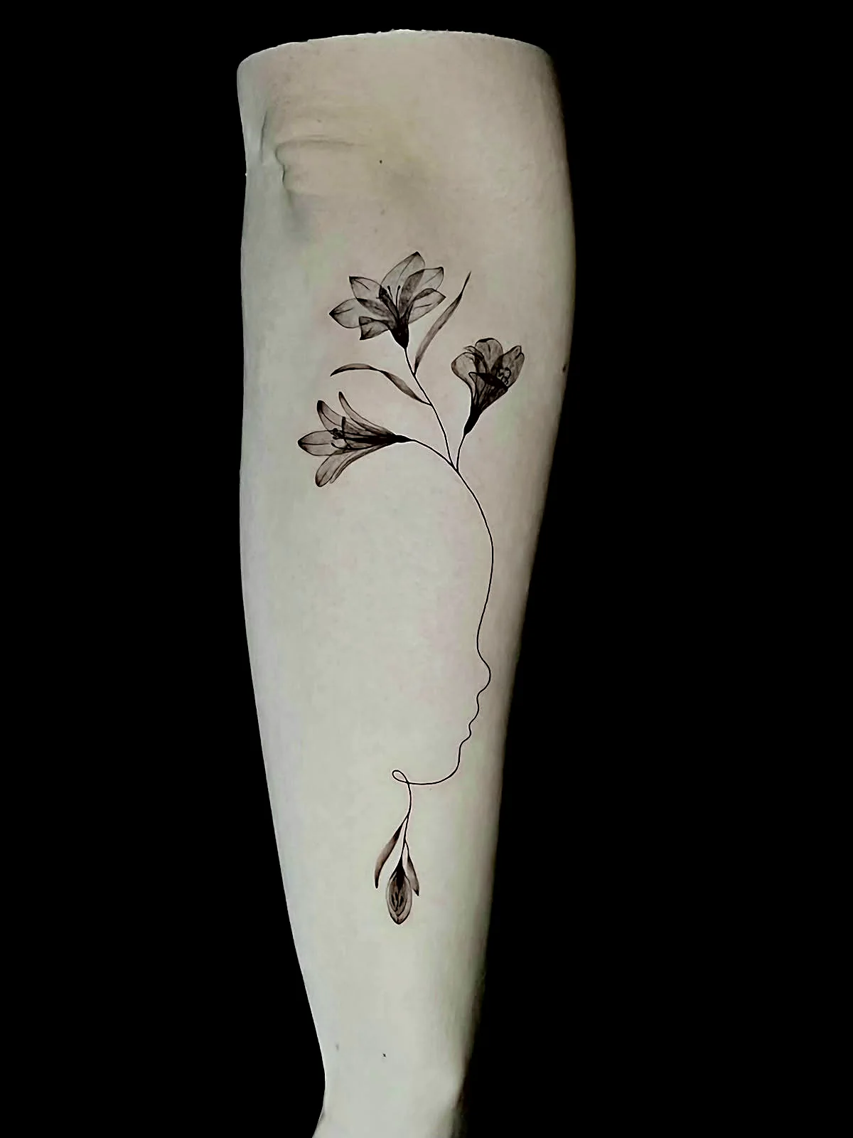 Fineline Lilien Tattoo mit Gesichts-Silhouette am Unterarm, gestochen von Silas bei EB Tattoo St. Gallen