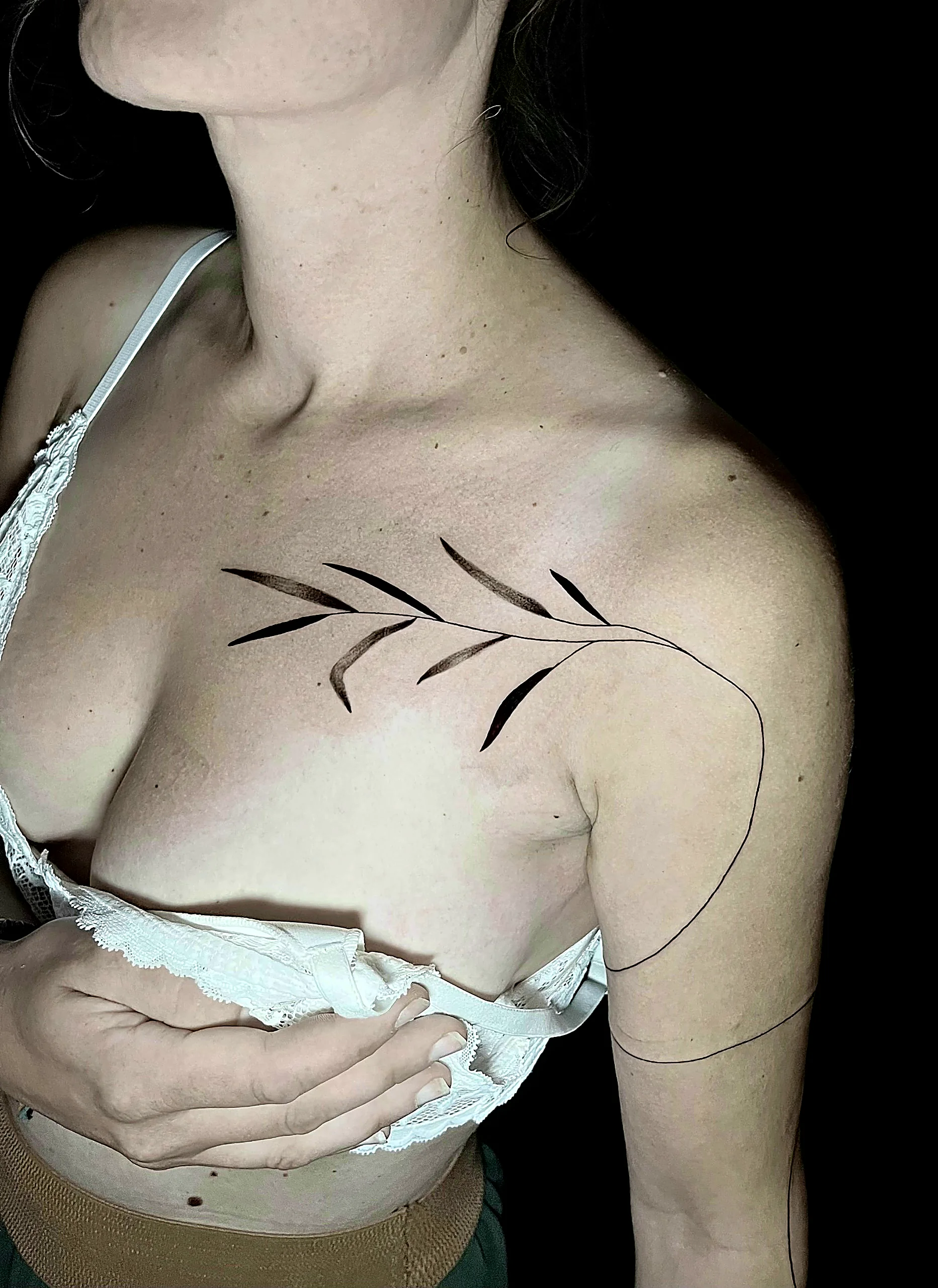 Fineline Tattoo eines botanischen Zweigs mit Blättern am Schlüsselbein, gestochen von Silas bei EB Tattoo St. Gallen