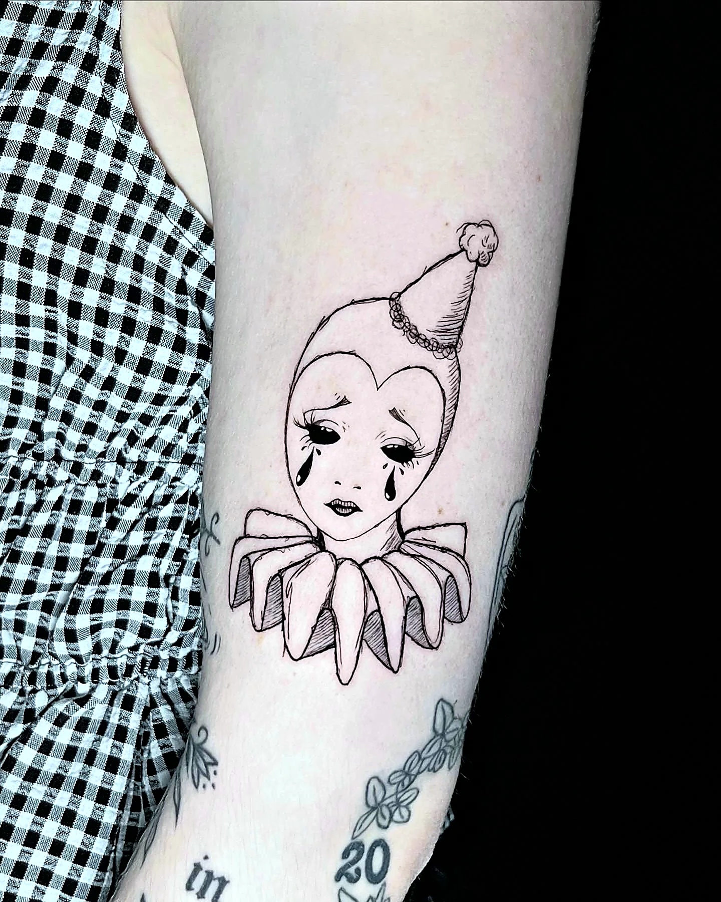 Pierrot Clown Tattoo im Lineart-Stil mit Herzgesicht am Oberarm, gestochen von Silas bei EB Tattoo St. Gallen